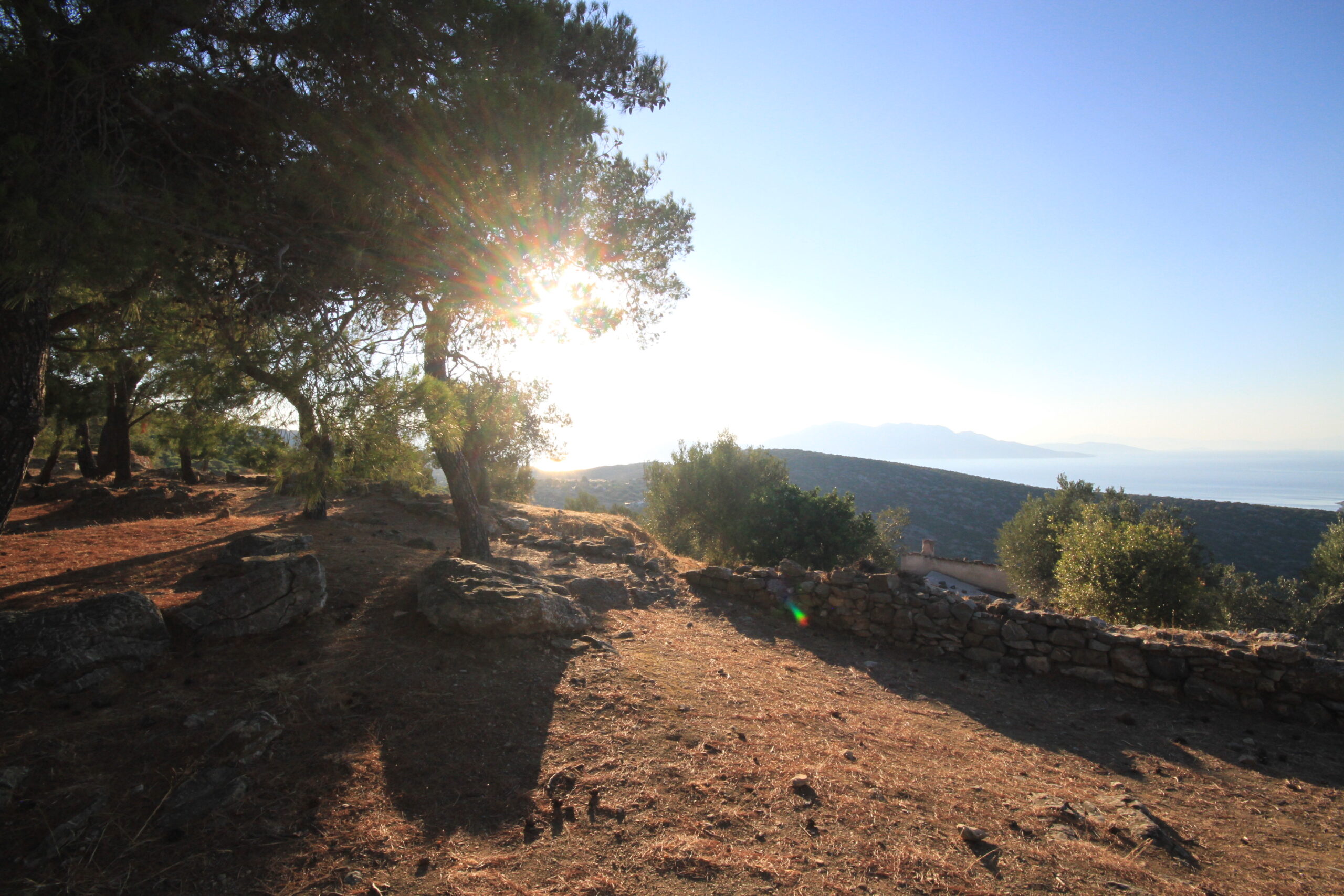 Header image, a late afternoon view from a hilltop on the Greek island of Poros overlooking a bay on the north coast.